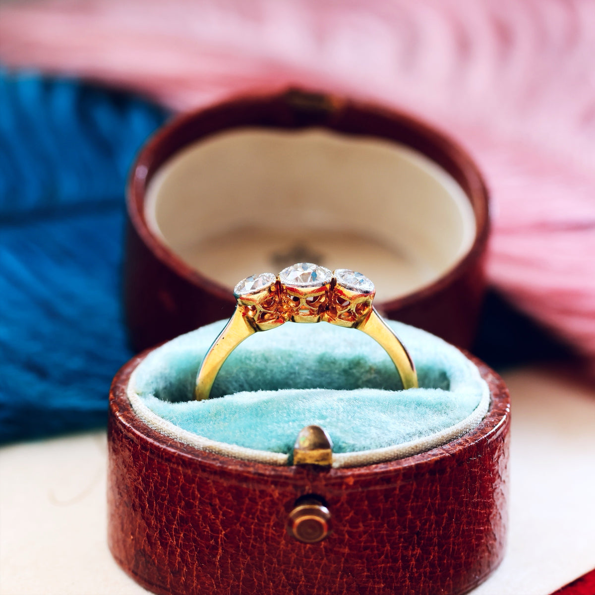 Gold ring with three diamonds in a brown jewelry box on a blurred background