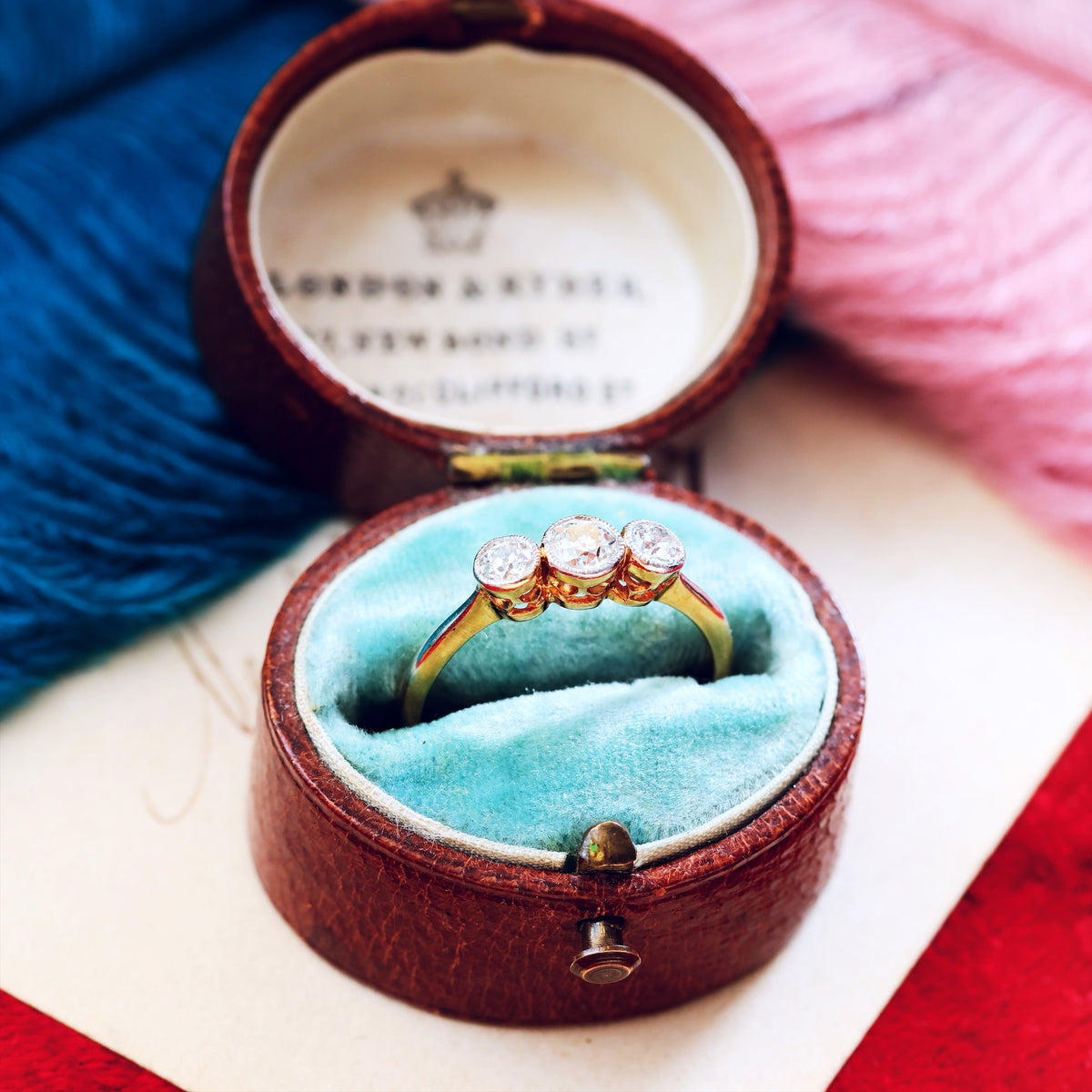 Gold ring with diamonds in a jewelry box on a colorful fabric background
